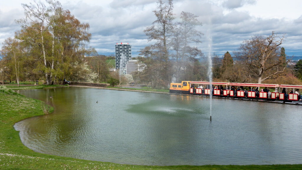 Erlebnisse und Entdeckungen eine Schmalspureisenbahn vor einem Teich im Killesberg Park in Stuttgart an Ostern.