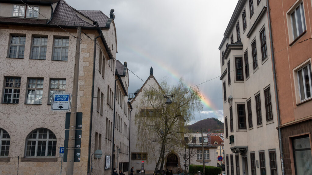 Rückseite des Universitätsgebäude Jenas über welches sich ein Regenbogen erstreckt.